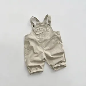 Détail de la salopette en coton kaki montrant la poche poitrine et les bretelles
