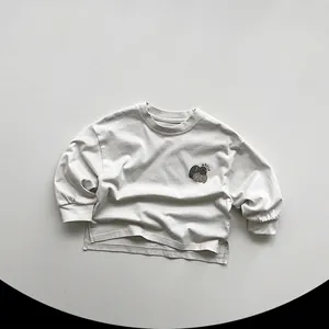 Detail of light grey cotton T-shirt featuring side slit hem and small apple print