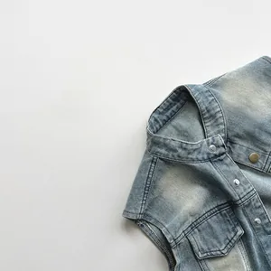 Détail d'un gilet en jean bleu clair vintage avec col montant et boutons-pression