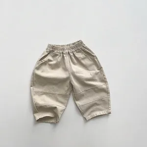 Dettaglio di pantaloni beige per bambini in cotone con vita elastica e tasche