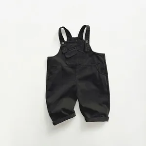 Détail de la salopette noire pour enfant avec bretelles réglables et poche frontale