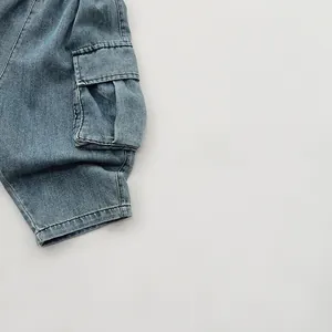 Dettaglio di pantaloni cargo in denim blu lavato per bambini con tasca laterale ampia