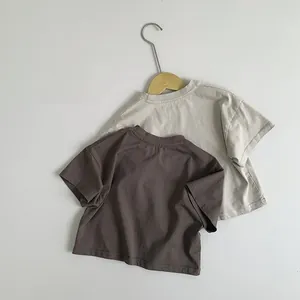 Détail de t-shirts en coton beige et marron foncé à col rond pour enfants sur cintres