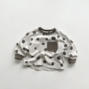 Detailed close-up of dot pattern fabric and ribbed cuffs on kids long sleeve tee