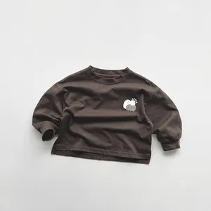 Close-up of kids' brown long-sleeve cotton tee with apple print and side slits