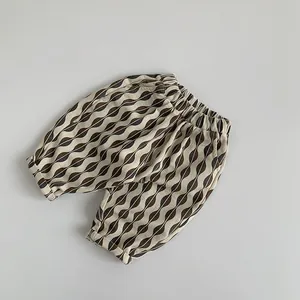 Gros plan d'un pantalon enfant en coton avec un motif de vagues marron et noir très élégant