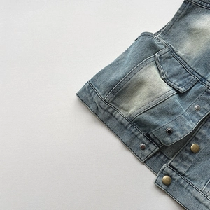 Détail d'un gilet en jean vintage avec grandes poches à rabat et boutons métalliques