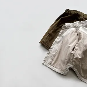 Flat lay of Korean-style kids cotton shorts in olive green and light beige colors