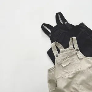 Détail de salopettes pour enfants en noir et beige avec bretelles réglables et poches