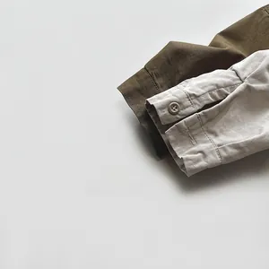 Detail view of cotton cuffs with buttons on olive green and beige children's shirts