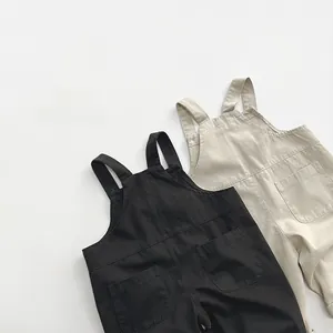 Vue à plat de salopettes pour bébé en coton noir et beige avec détail de poche frontale