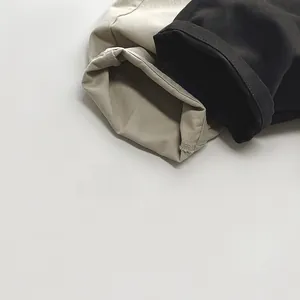 Détails des revers en sergé de coton et coutures sur salopettes enfant beige et noir
