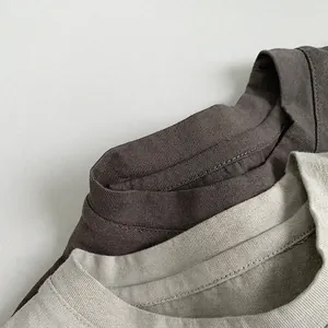 Gros plan détaillé des cols ronds côtelés sur des t-shirts en coton pour enfants en gris