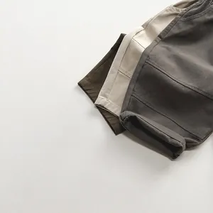Dettaglio di pantaloncini in cotone per bambini nei colori verde oliva, beige e grigio scuro