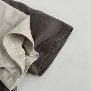 Détail de la couture à double aiguille sur les poignets des t-shirts beige et marron