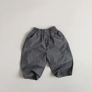 Detail of kids casual cotton pants featuring elastic waist and decorative buttons