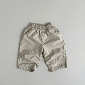 Detail view of children's cotton pants showing elastic waist and button stitching