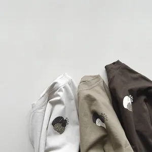 Detail of three cotton T-shirts in earth tones with vintage apple graphic and lettering