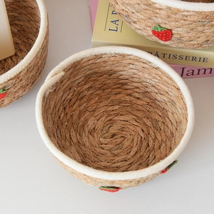 Detailaufnahme von geflochtenem Korb mit Erdbeerstickerei und weißem Strickrand