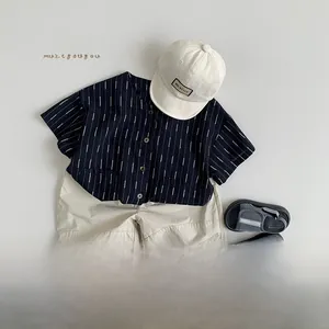 Detailed flat lay of a kids navy striped shirt, beige shorts, cap and sandals set