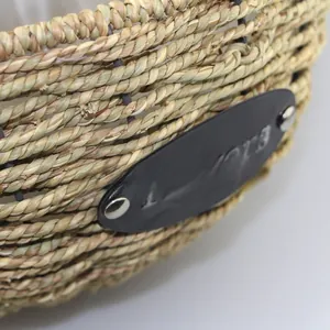 Close-up of hand-woven wicker hanging basket featuring a leather 'Flowers' label and rivets