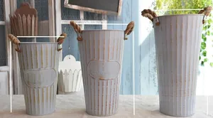 Detail of vintage cream metal garden flower pails with jute rope handles and ribbed texture