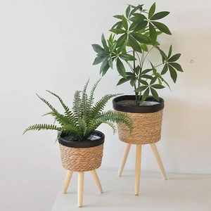 Close-up of woven rattan flower pot set with black leather edge and tripod wood legs