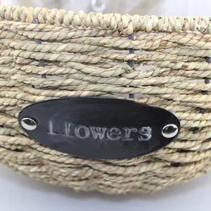 Detailed close-up of handmade wicker hanging basket with oval Flowers metal nameplate