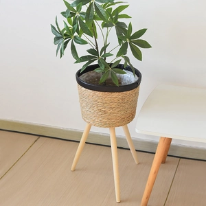 Detail of Nordic woven plant stand with natural straw basket and solid wood tripod legs