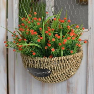 Handwoven wall basket with greenery and red flowers on vintage wooden door
