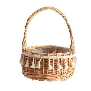 Handmade wicker flower basket with white fringe tassels and plastic liner in natural wood color