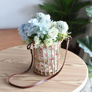 Detalle de la cesta de flores de mimbre tejida con forro floral rosa y correa de cuero