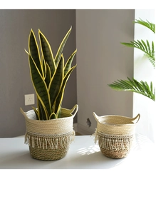 Close-up of woven straw plant pot set with tassels and handles for home decor