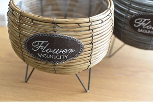 Close-up of hand-woven wicker planters with waterproof liners and black metal tripods