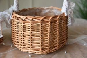 Detail of woven wicker flower basket with elegant white lace bow and protective lining