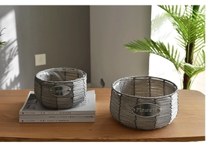 Detail of grey hand-woven flower baskets with waterproof liners and metal brand plates