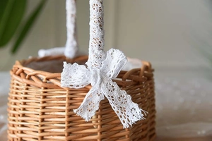 Detail of hand-woven wicker flower basket with white lace bow and natural textures