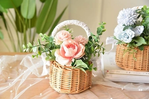 Detail of woven wicker flower basket with delicate white lace handle and silk peonies
