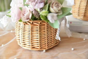 Close-up of a handmade wicker basket with delicate white lace trim and soft floral decor
