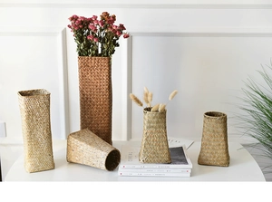 Detailed view of four handmade woven straw vases in natural and dark brown wood tones