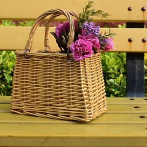 Detailed macro shot of a handmade wicker basket bag with floral decor on a wooden bench