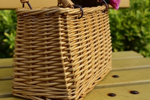 Macro shot of a rectangular handmade wicker flower basket on a bright yellow outdoor bench