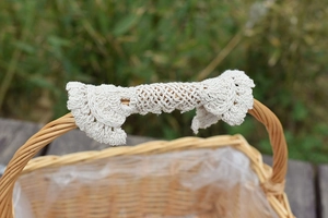 Close-up of beige crochet handle cover on a woven flower basket with lace detail