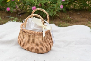 Detail of woven rattan basket with white drawstring linen liner and decorative bow accent
