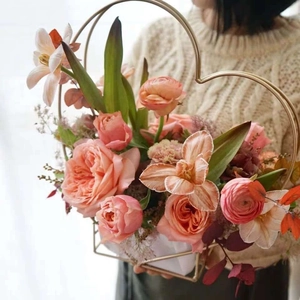 Close-up of golden heart-shaped metal flower basket with fresh pink roses and flowers