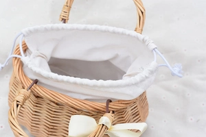 Detailed macro view of woven willow basket with white drawstring lining and ribbon bow