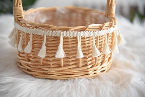 Detail view of woven wicker flower basket with white tassel fringe and interior plastic liner