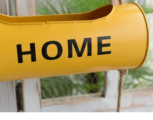 Detail of yellow iron wall hanging flower bucket with HOME text and hemp rope hanger