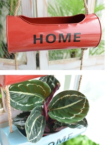 Close-up of vintage hanging metal planters with rope and HOME lettering decor