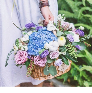 Detail of hand-woven wicker flower basket featuring blue hydrangea and pink roses